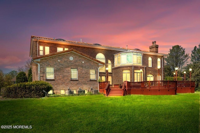 8 Tiberon Dr, Holmdel, NJ 07733 - back of property at dusk with brick siding, a wooden deck, a chimney, and a lawn