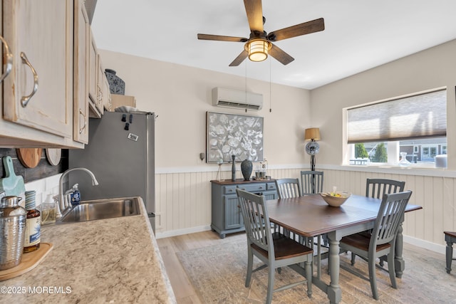 dining space featuring ceiling fan, a wall mounted AC, wainscoting, and light wood finished floors