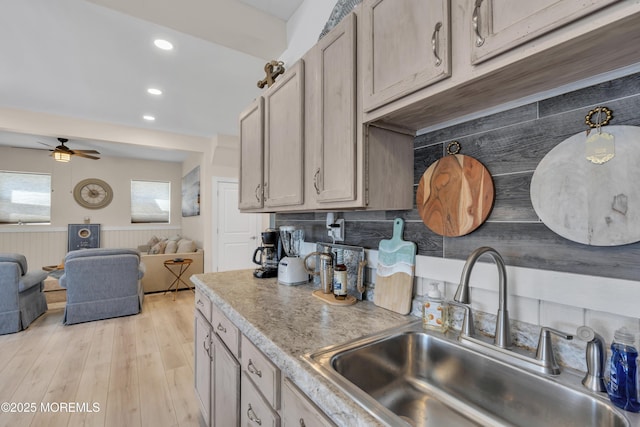 kitchen with a sink, light wood finished floors, a ceiling fan, and open floor plan
