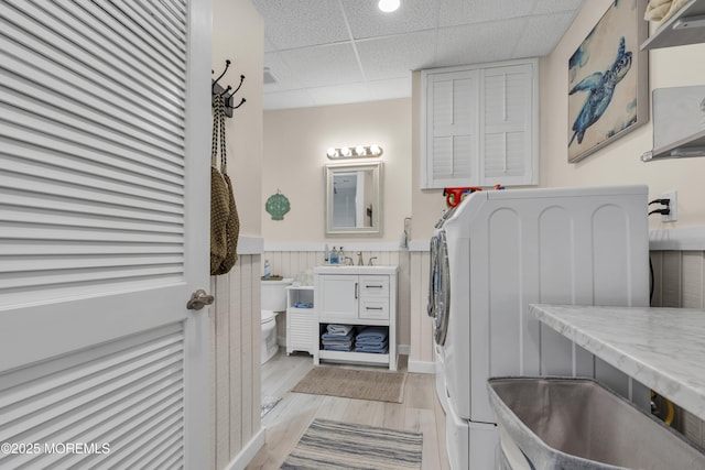 bathroom with a paneled ceiling, wainscoting, wood finished floors, vanity, and toilet