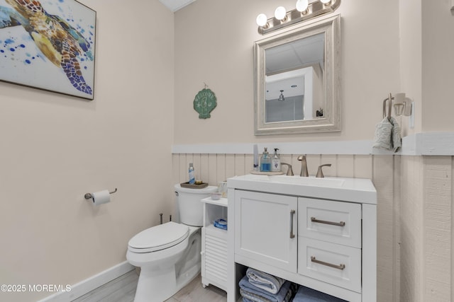 bathroom featuring a wainscoted wall, vanity, and toilet
