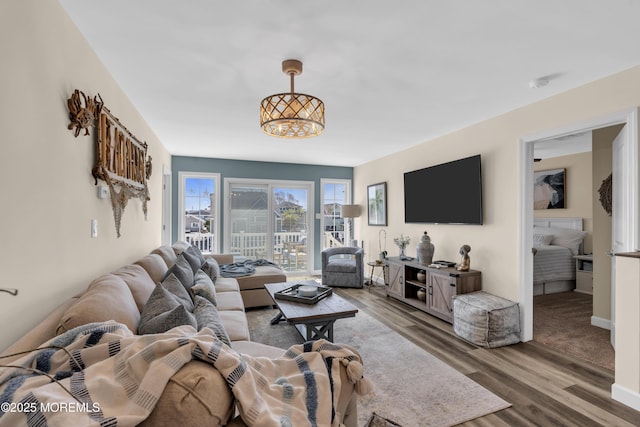 living area with baseboards, a chandelier, and wood finished floors