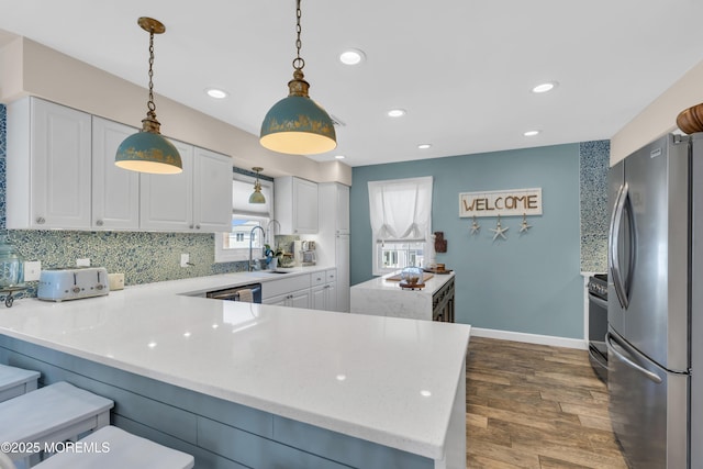 kitchen featuring decorative backsplash, white cabinets, appliances with stainless steel finishes, and a wealth of natural light
