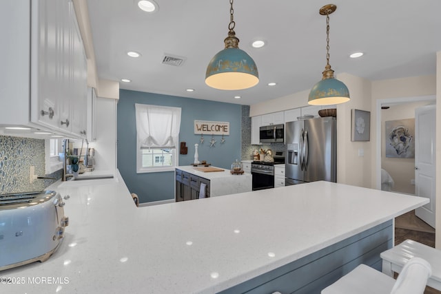 kitchen with visible vents, decorative backsplash, white cabinetry, a sink, and stainless steel appliances