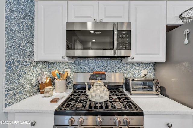 kitchen featuring white cabinets, appliances with stainless steel finishes, a toaster, and tasteful backsplash