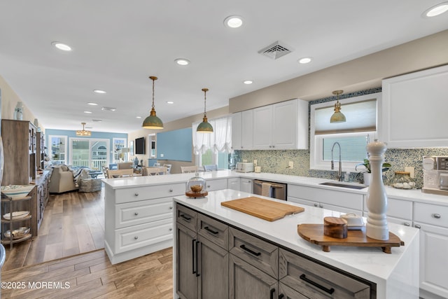 kitchen featuring visible vents, a sink, white cabinets, and light countertops