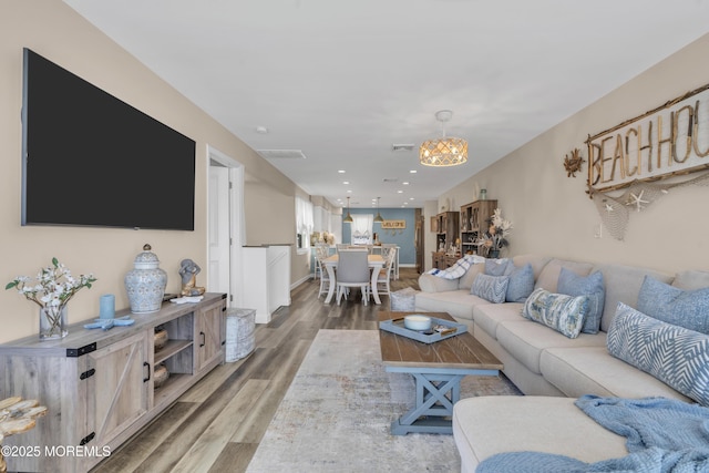 living room with visible vents, wood finished floors, baseboards, recessed lighting, and a notable chandelier