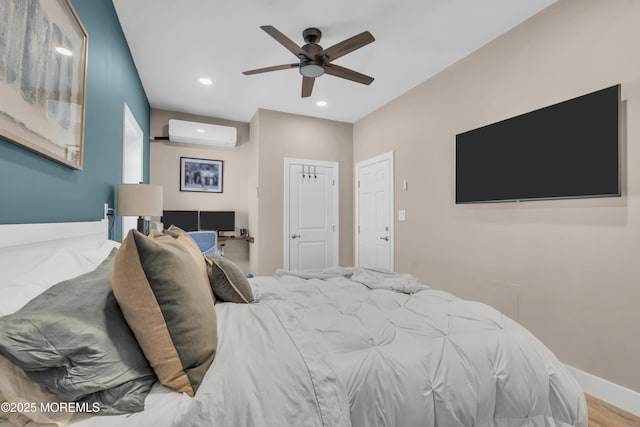 bedroom featuring ceiling fan, an AC wall unit, recessed lighting, baseboards, and wood finished floors