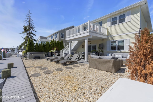 back of house with outdoor lounge area, a balcony, a patio, stairs, and a hot tub