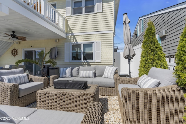 view of patio / terrace featuring fence, outdoor lounge area, an AC wall unit, a balcony, and a ceiling fan