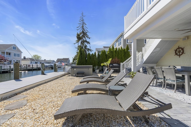 view of patio / terrace with stairs, a water view, a hot tub, and a boat dock