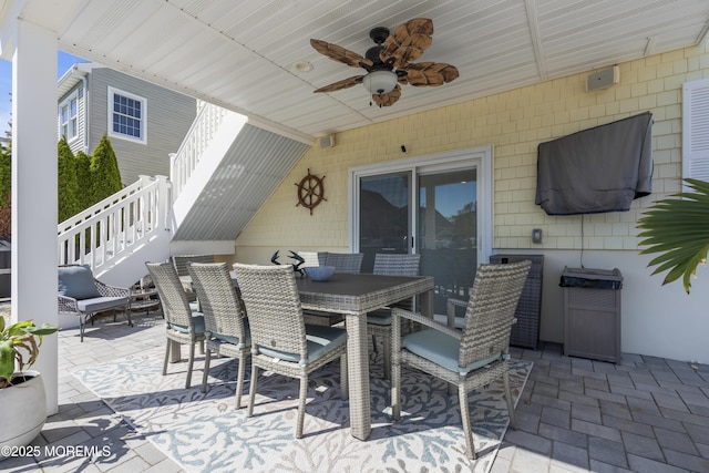 view of patio featuring a ceiling fan, outdoor dining area, and stairs
