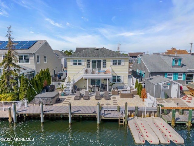 rear view of house with fence, stairs, a deck with water view, an outdoor living space, and a patio