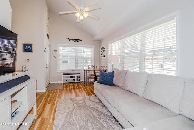 living room with baseboards, a ceiling fan, light wood finished floors, and lofted ceiling