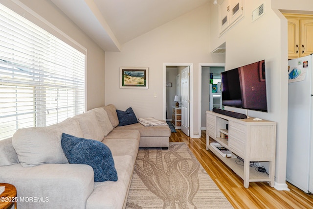 living room with baseboards, visible vents, lofted ceiling, and light wood-type flooring