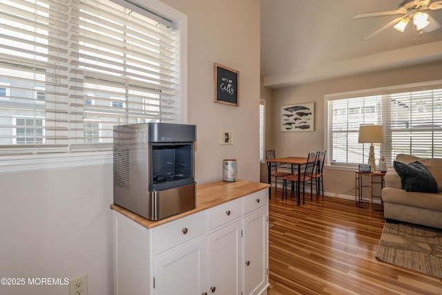 kitchen with white cabinets, ceiling fan, light wood finished floors, baseboards, and butcher block counters