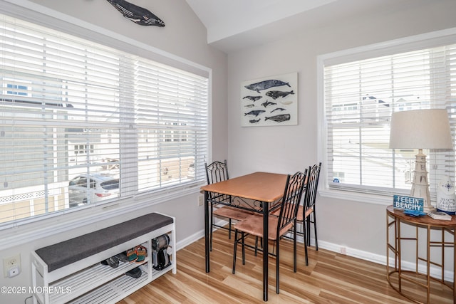 dining area with baseboards, vaulted ceiling, and wood finished floors