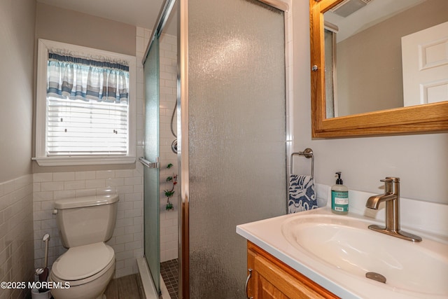 full bath with vanity, tile walls, a stall shower, and toilet