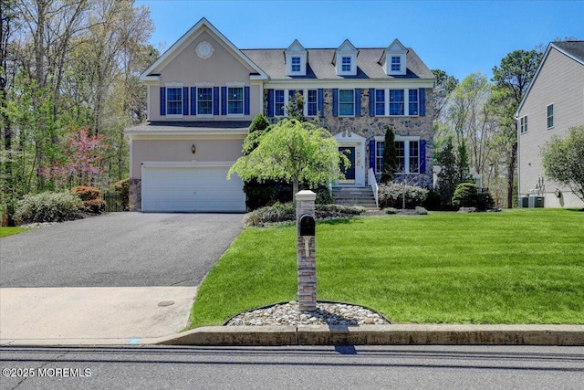 view of front facade featuring an attached garage, a front lawn, stucco siding, cooling unit, and driveway