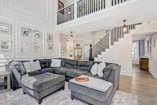 living area with stairway, crown molding, and a decorative wall