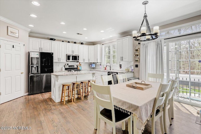 dining room with recessed lighting, ornamental molding, light wood finished floors, and a chandelier