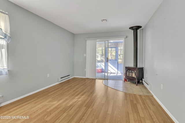 3 Tudor Ct, Brick, NJ 08723 - interior space featuring visible vents, a baseboard heating unit, light wood finished floors, and a wood stove