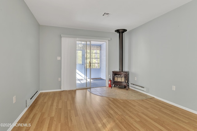 3 Tudor Ct, Brick, NJ 08723 - interior space featuring a wood stove, a baseboard heating unit, light wood finished floors, and visible vents