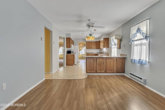 3 Tudor Ct, Brick, NJ 08723 - kitchen with brown cabinetry, a ceiling fan, baseboard heating, a peninsula, and light wood-style floors