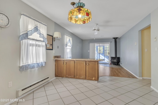 3 Tudor Ct, Brick, NJ 08723 - kitchen with brown cabinets, a wood stove, a peninsula, baseboards, and a baseboard radiator