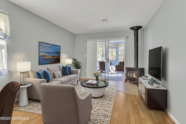 3 Tudor Ct, Brick, NJ 08723 - living area featuring baseboards, a wood stove, light wood-style flooring, and visible vents