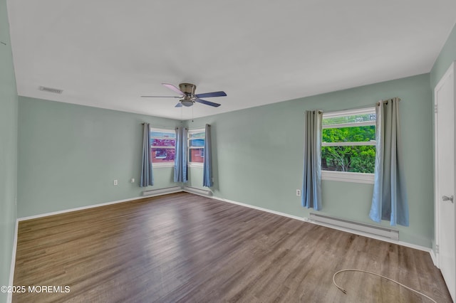 empty room featuring a baseboard radiator, healthy amount of natural light, wood finished floors, and ceiling fan
