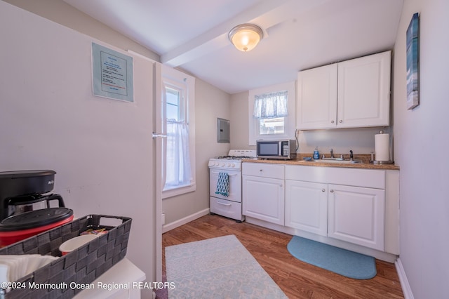 kitchen with gas range gas stove, stainless steel microwave, white cabinets, a sink, and light wood finished floors