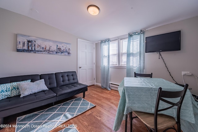 living area with baseboards, wood finished floors, and a baseboard radiator