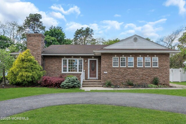 view of front facade with stone siding, a chimney, and entry steps