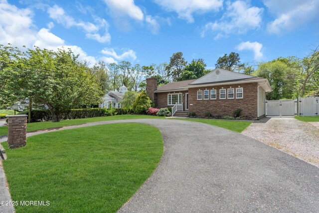 ranch-style home with a gate, curved driveway, brick siding, and a chimney