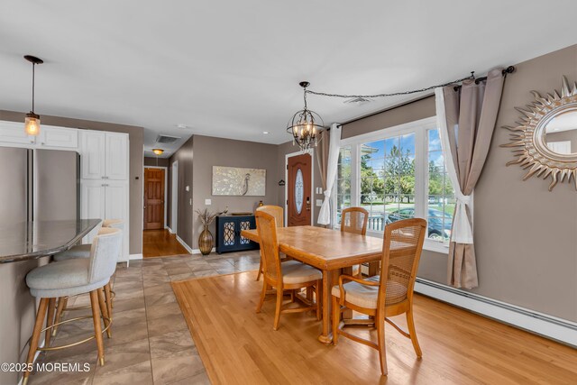 dining room featuring a baseboard heating unit, a chandelier, and baseboards
