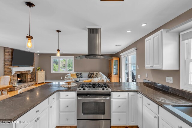 kitchen with stainless steel gas range, island exhaust hood, open floor plan, recessed lighting, and white cabinets