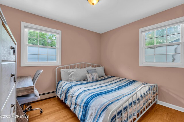 bedroom featuring wood finished floors, baseboards, and baseboard heating