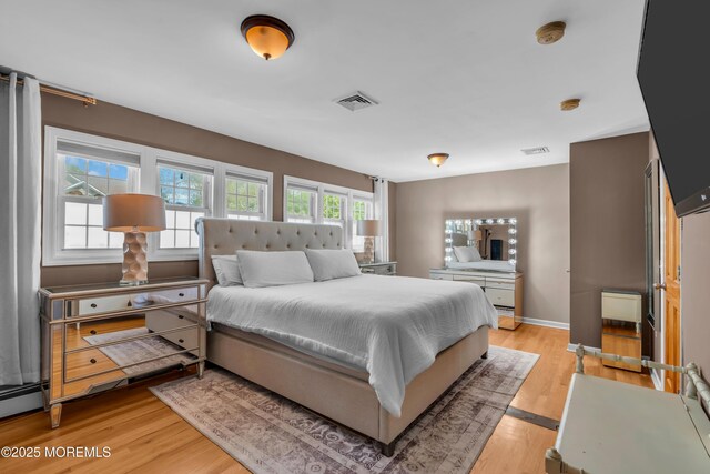 bedroom featuring light wood-style floors, baseboard heating, and baseboards