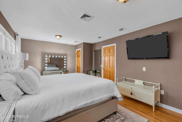 bedroom featuring light wood finished floors and baseboards