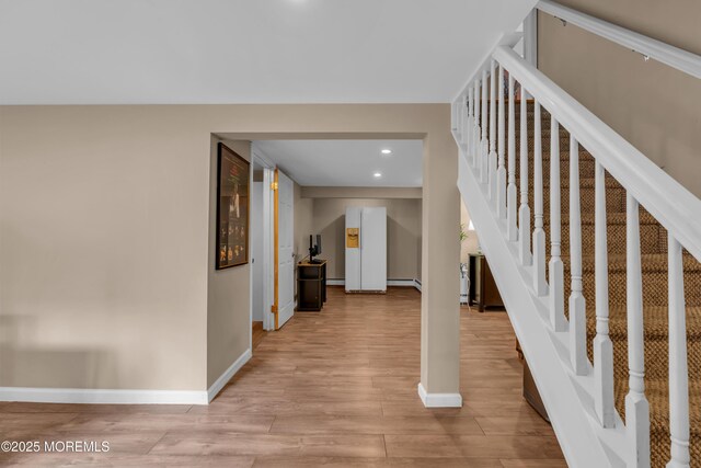 foyer entrance with light wood finished floors, baseboards, stairway, a baseboard radiator, and recessed lighting