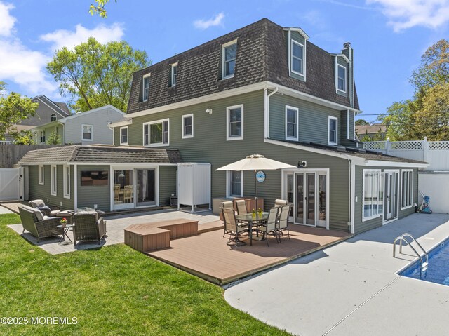 rear view of property featuring fence, a shingled roof, an outdoor hangout area, a deck, and mansard roof