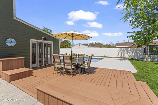 deck with a fenced backyard, a fenced in pool, and outdoor dining space