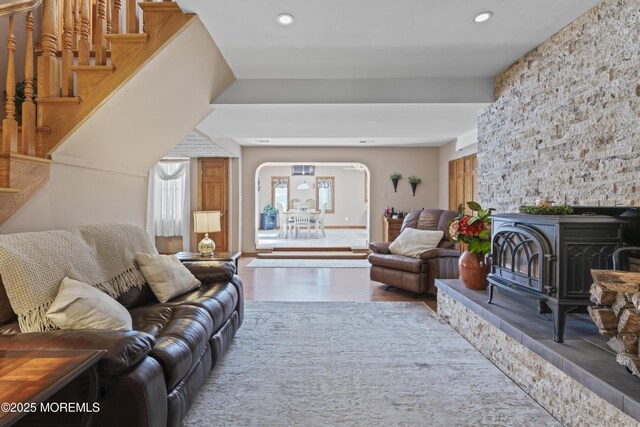 living area with recessed lighting, a wood stove, arched walkways, and wood finished floors
