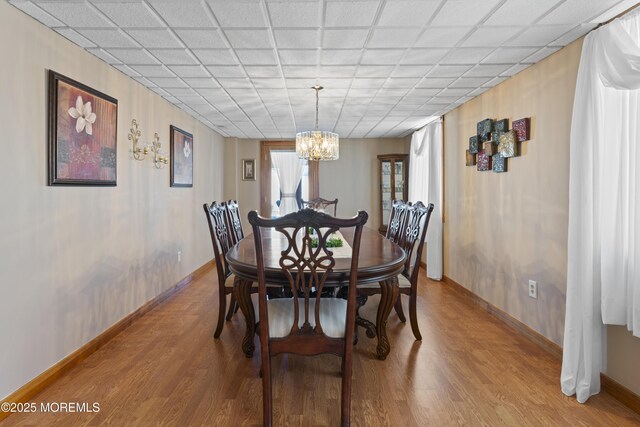 dining room with baseboards, a chandelier, and light wood finished floors