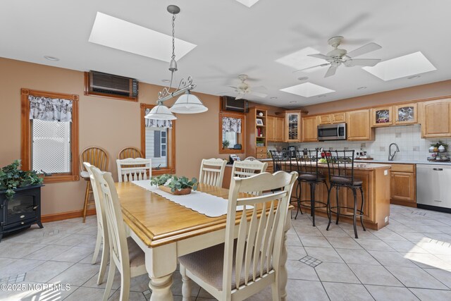 dining area featuring a skylight, light tile patterned floors, ceiling fan, and a wall mounted AC