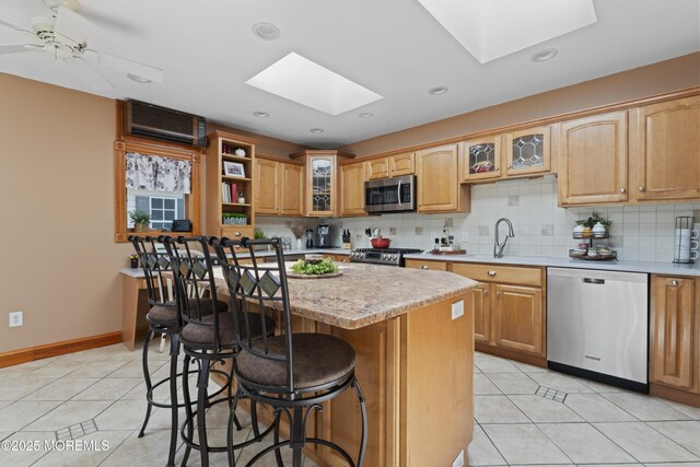 kitchen featuring a sink, light tile patterned floors, a skylight, and stainless steel appliances