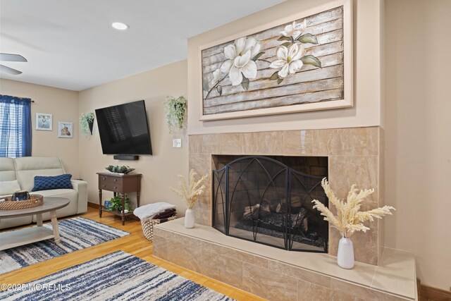 living area with recessed lighting, ceiling fan, wood finished floors, and a fireplace