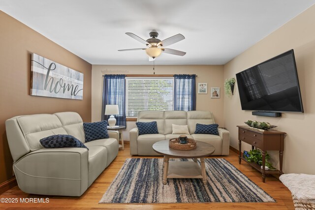 living room with a ceiling fan and light wood-style flooring