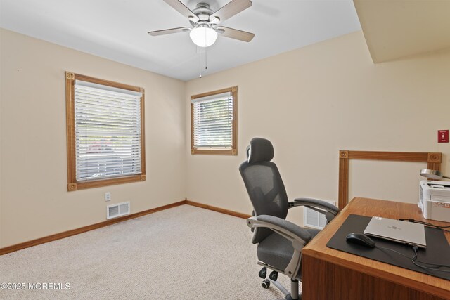 carpeted home office featuring visible vents, baseboards, and ceiling fan